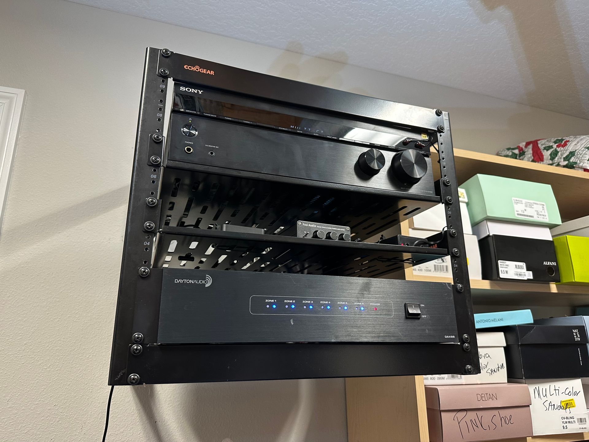 A black amplifier is sitting on top of a shelf in a room.