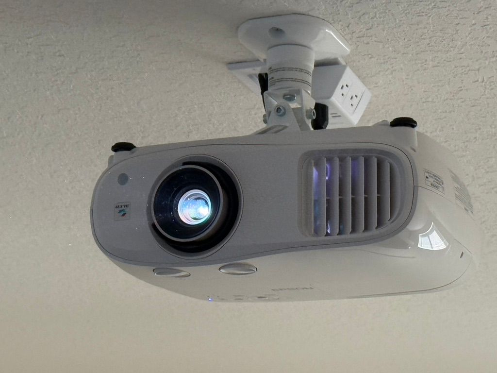 A white projector is hanging from the ceiling.