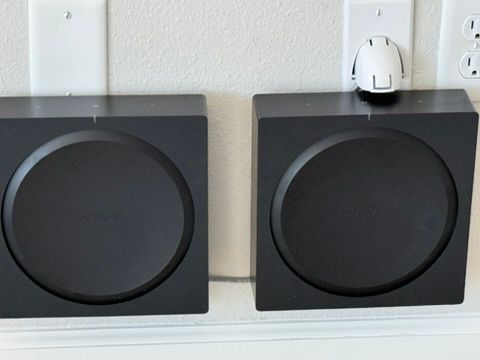 Two black speakers are sitting next to each other on a wall.