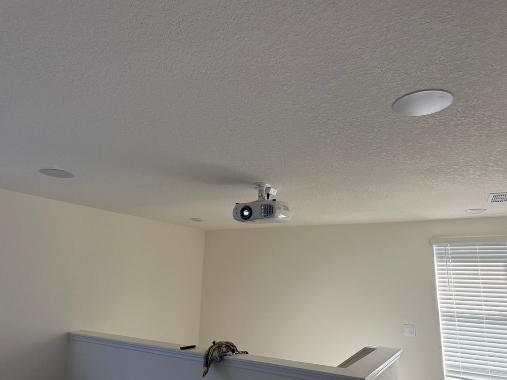 A projector is hanging from the ceiling of a living room.