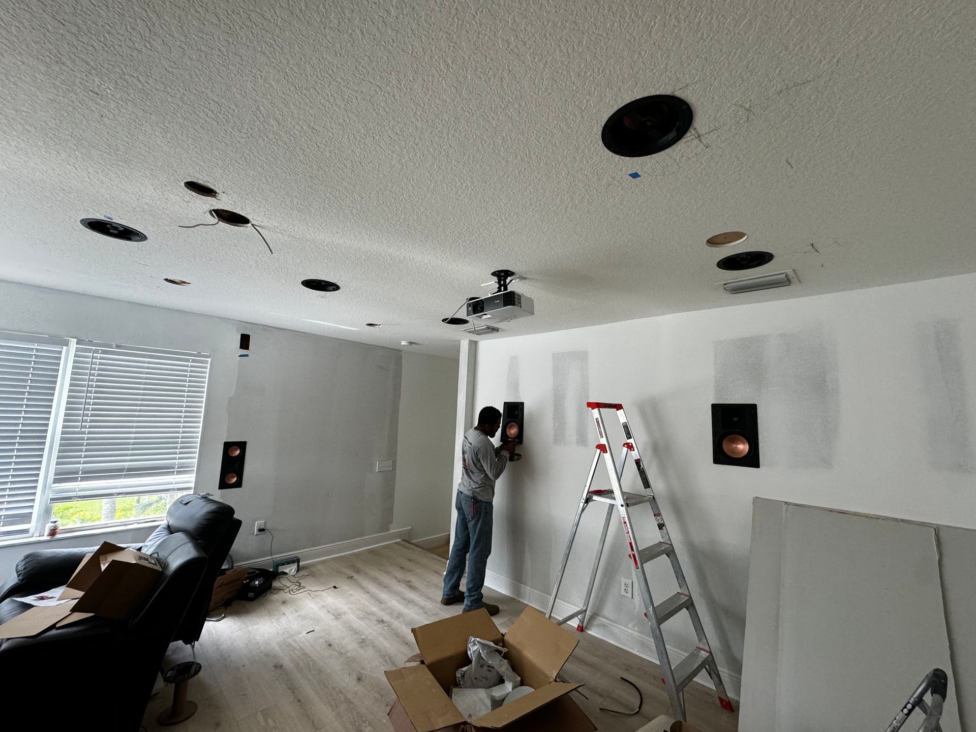 A man is installing speakers in a living room.