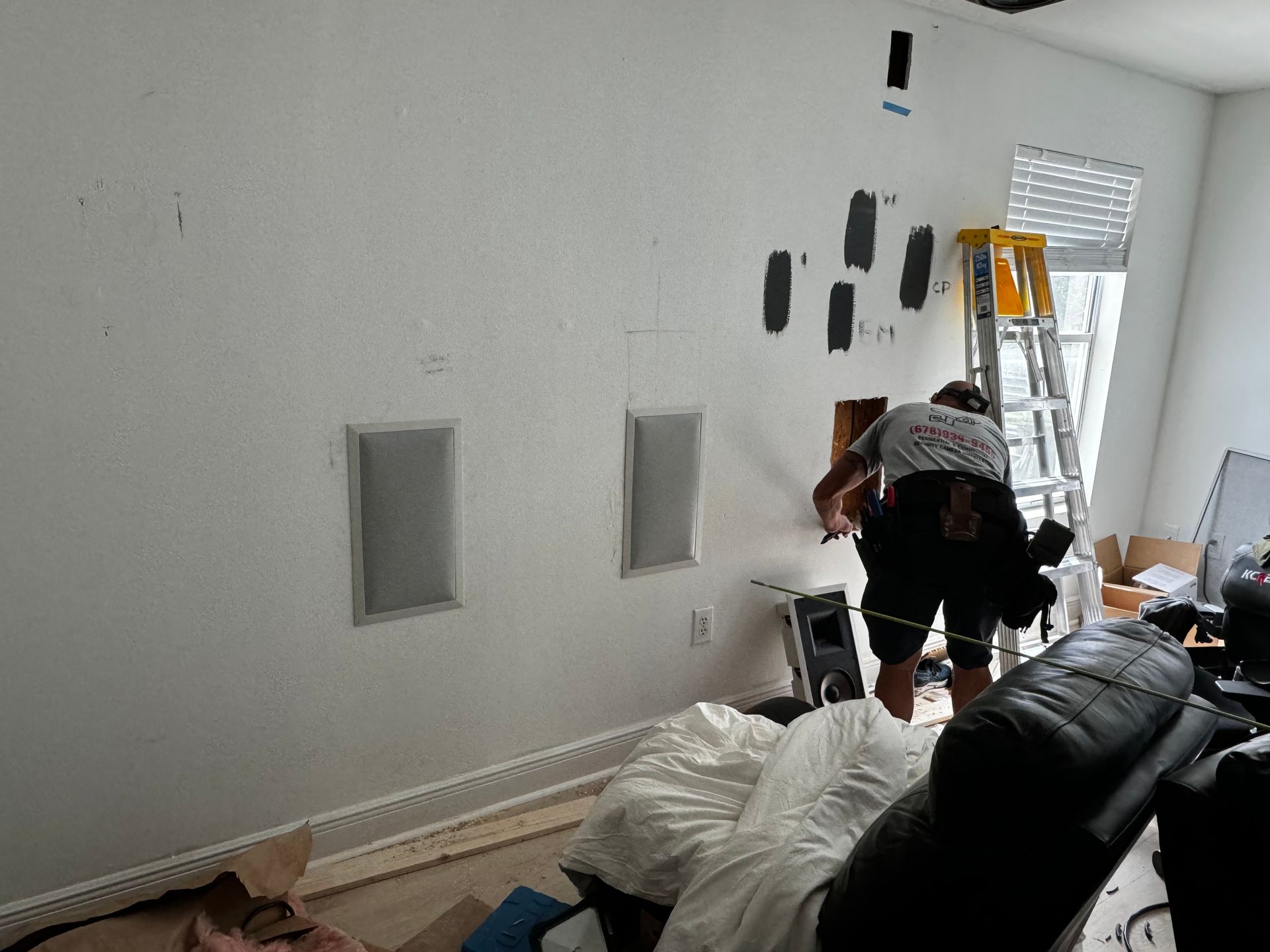 A man is installing speakers in a living room.