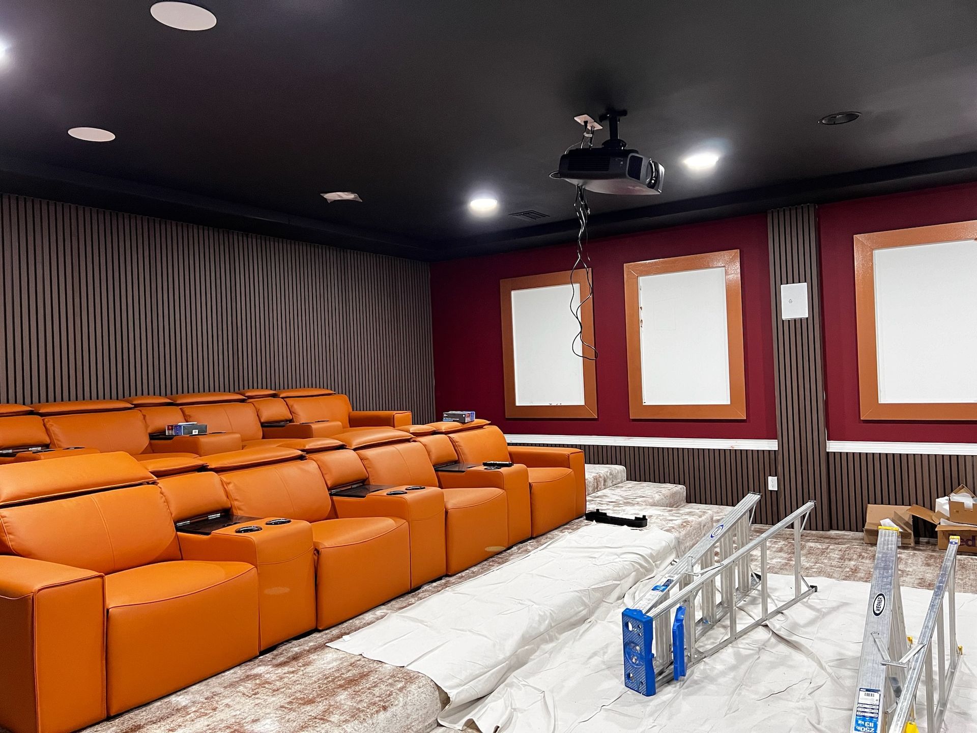 A home theater with orange seats and a projector hanging from the ceiling.