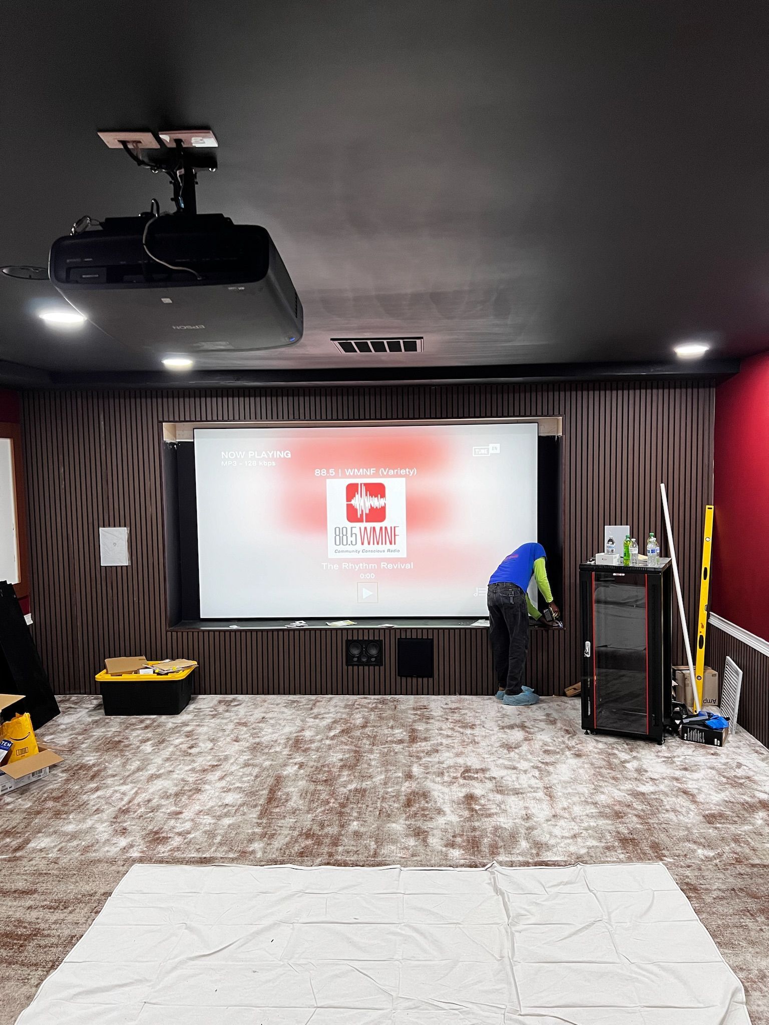 A man is working on a projector screen in a home theater.