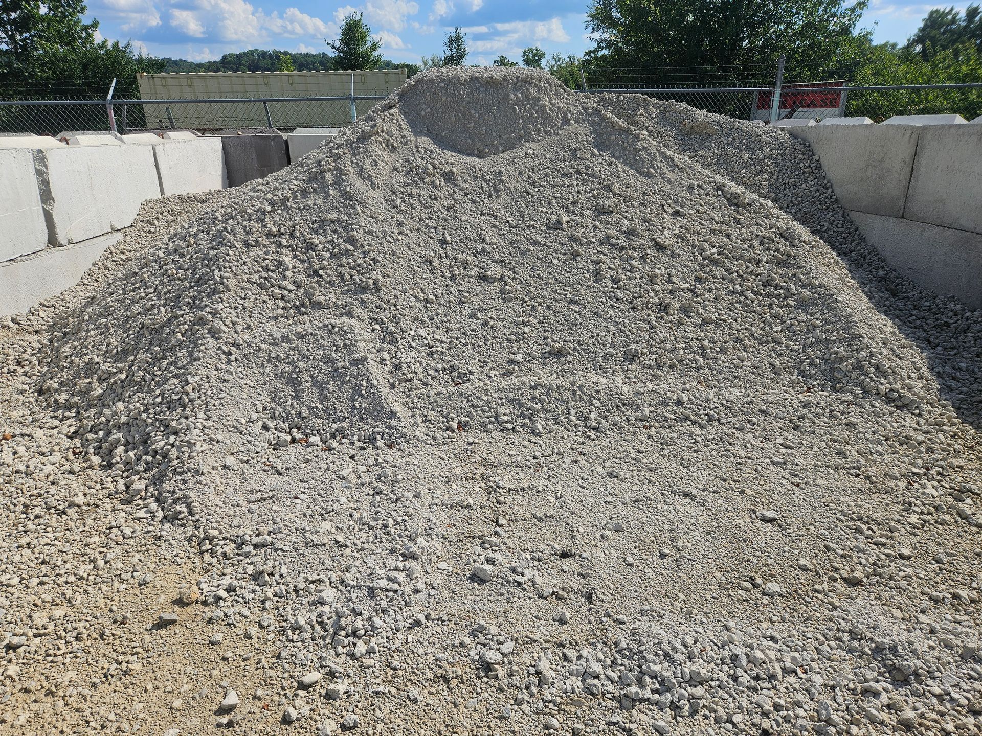 Pile of gray gravel, contained by concrete blocks, outdoors.