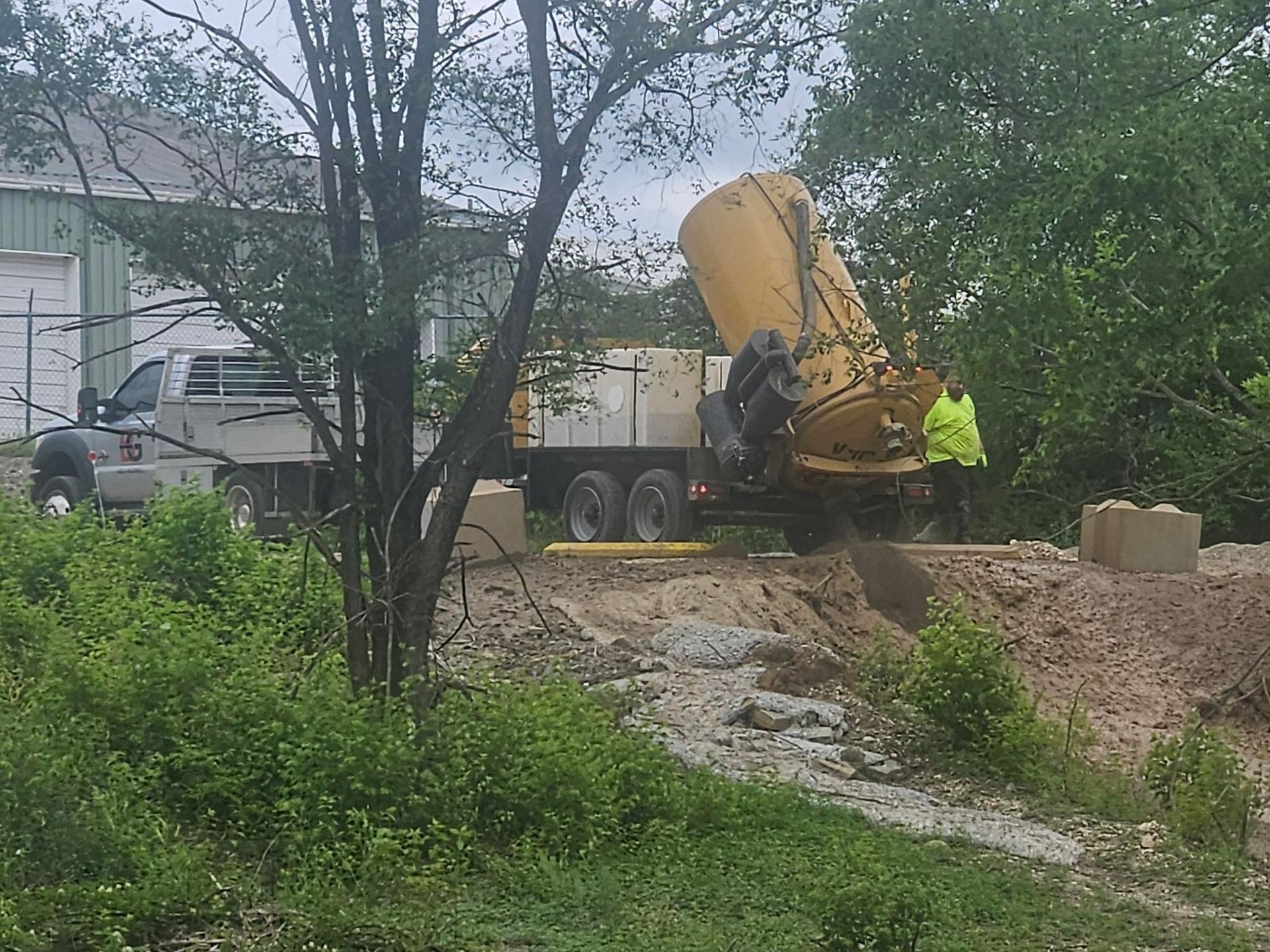 A large yellow truck is driving through a dirt field.