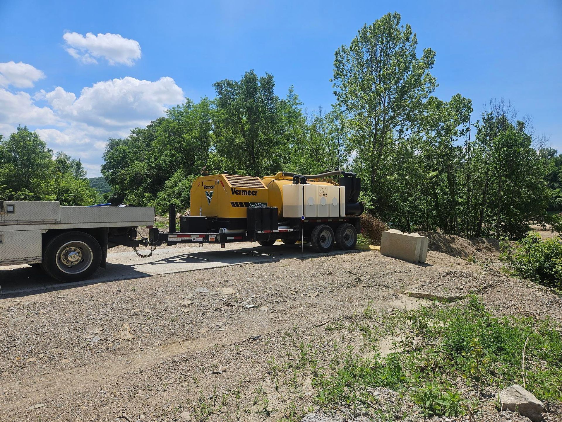 A yellow and white truck is parked in a gravel lot.