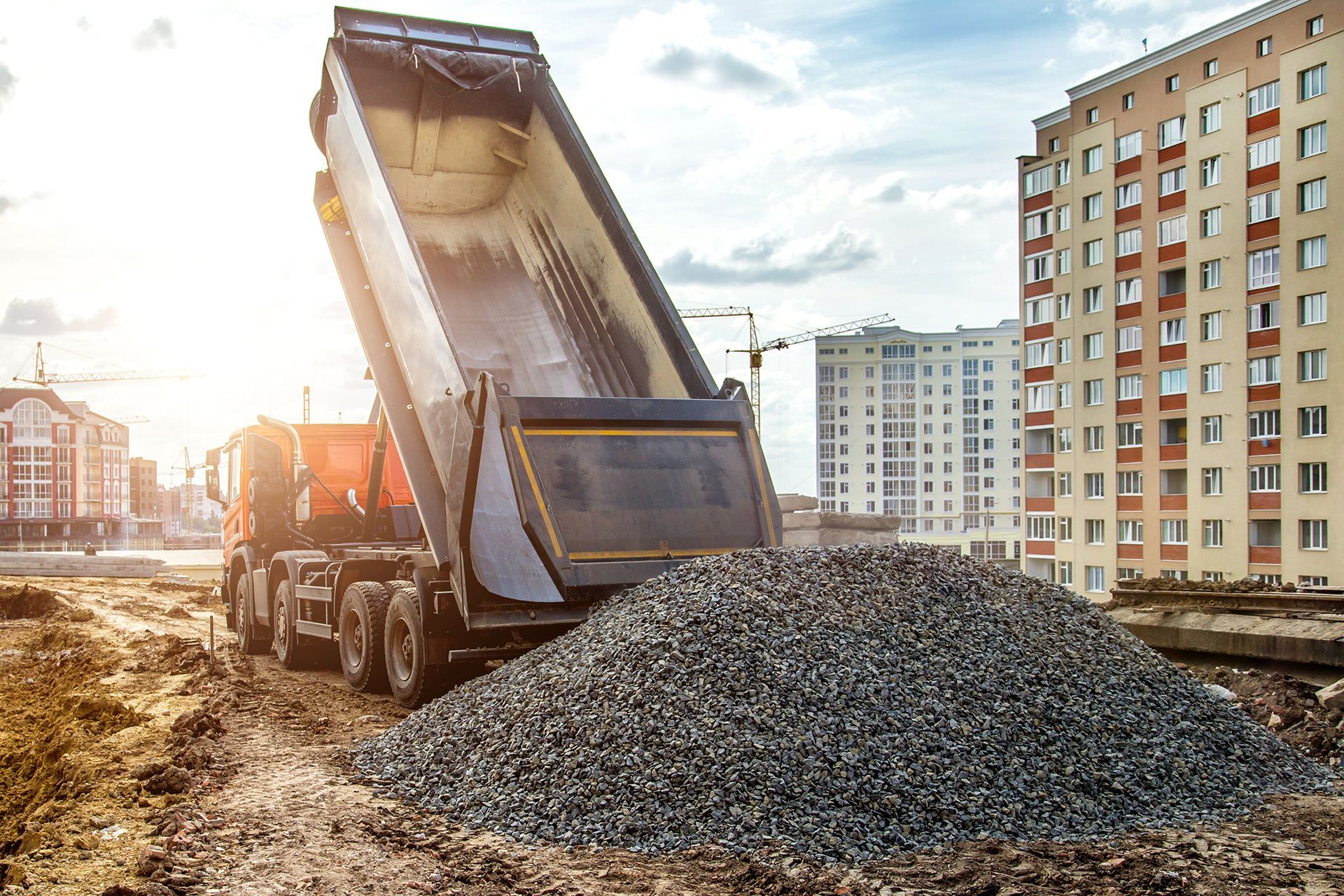 A dump truck is dumping gravel on a construction site.