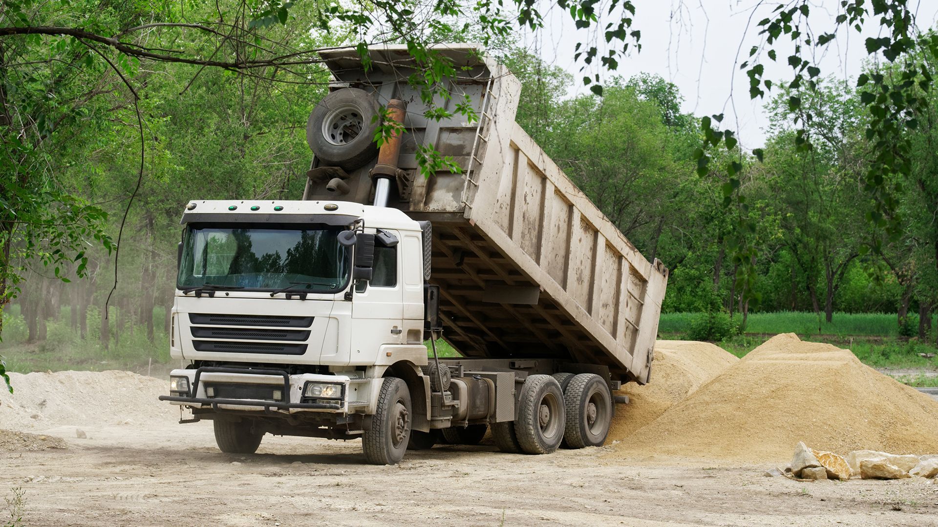 A dump truck is dumping dirt on a construction site.