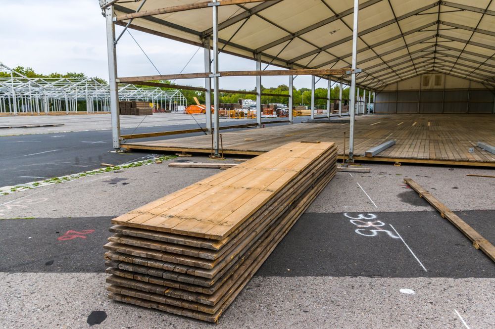 Large Tent Under Construction With Stacked Wooden Planks — T & T Scaffolding in Gordonvale, QLD