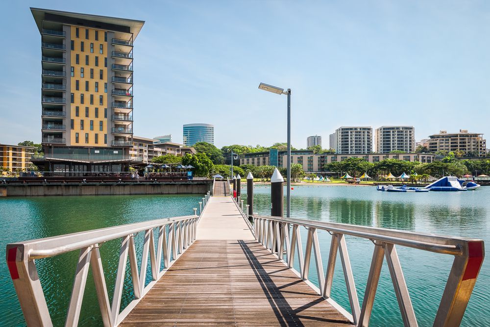 A Dock Leading to A Body of Water with A Building in The Background — T & T Scaffolding in Darwin, NT