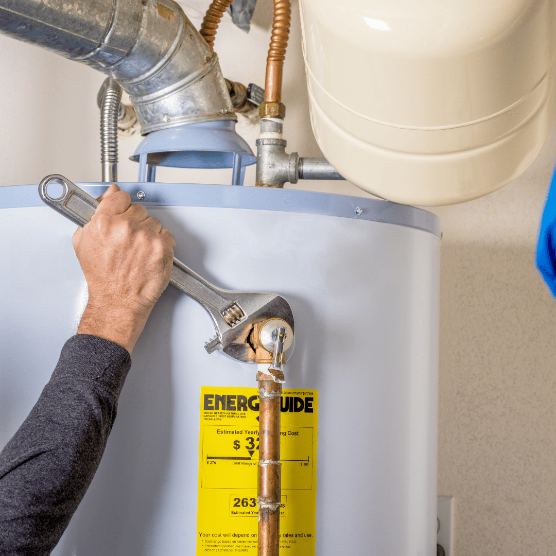 Person using a wrench on a water heater, indoors.