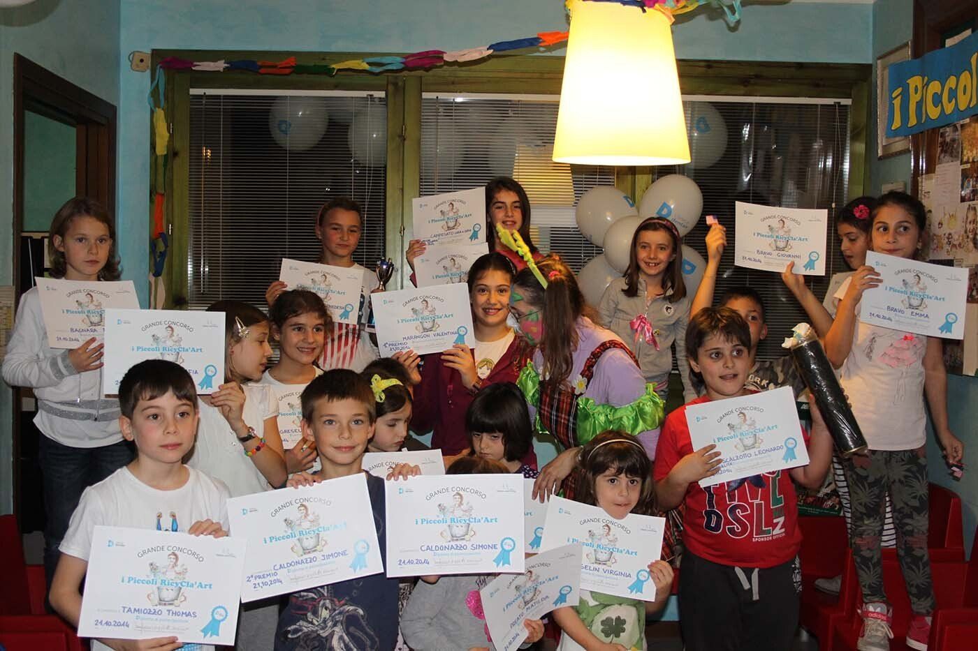 Un gruppo di bambini posa per una foto mentre tengono in mano i loro disegni.