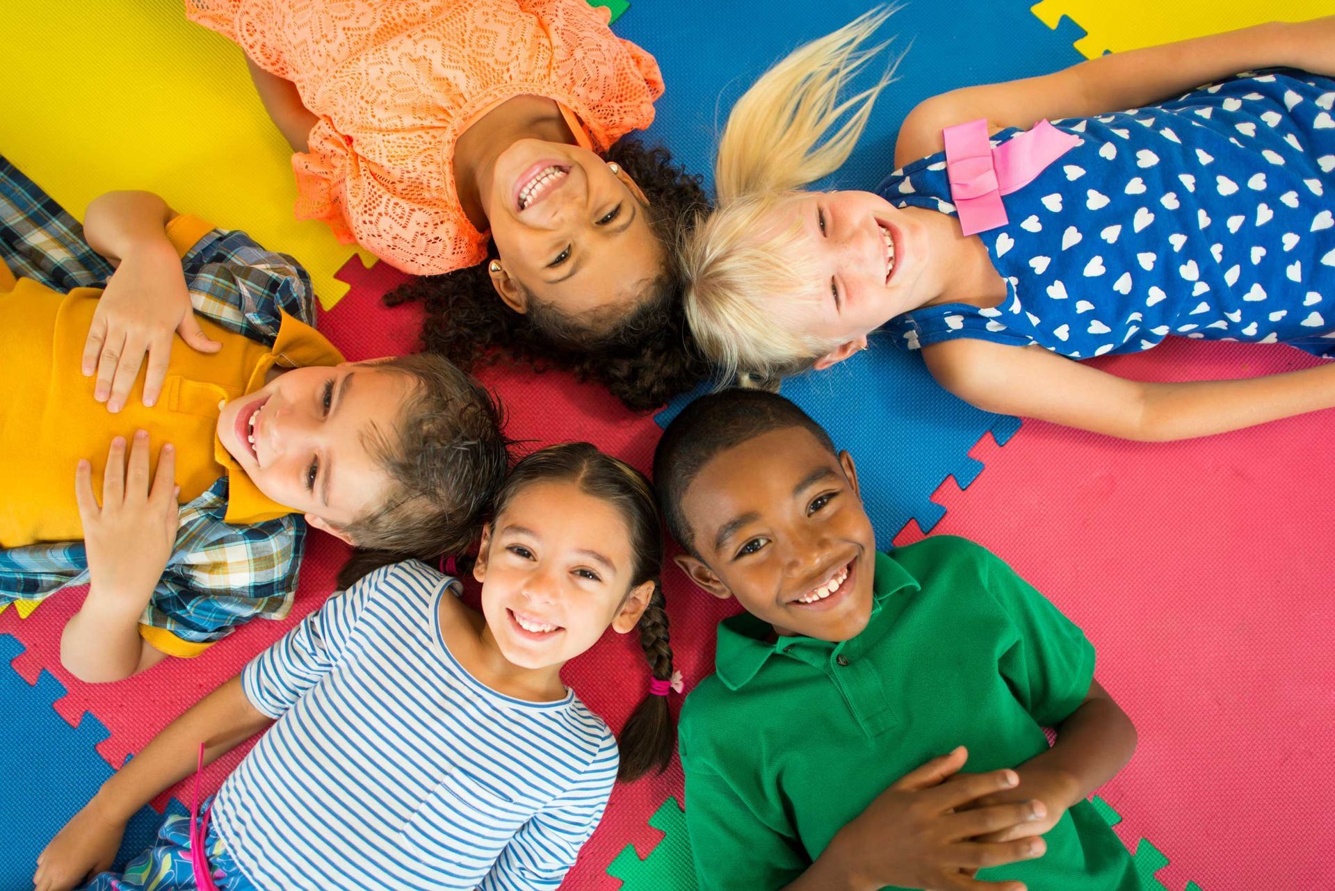 Un gruppo di bambini è sdraiato sul pavimento in cerchio.