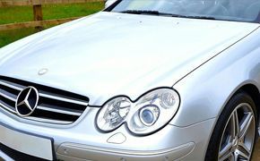 A silver mercedes convertible is parked on the side of a road