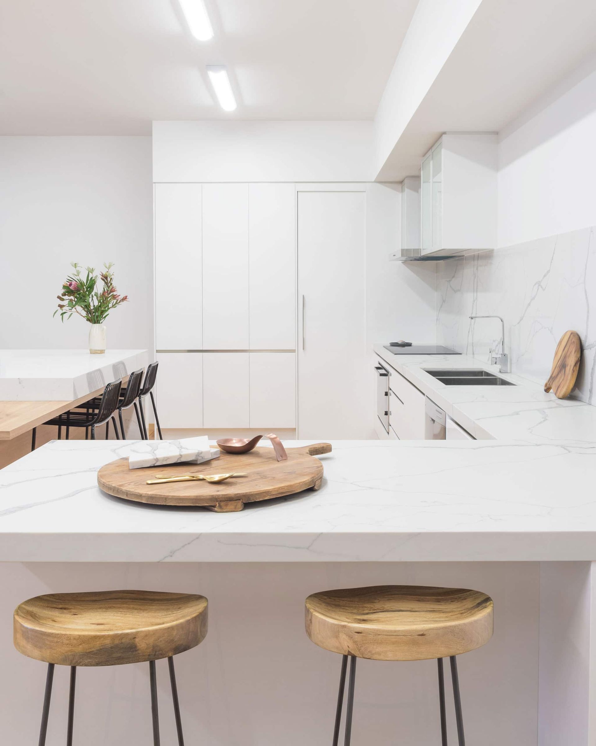 Modern White Kitchen With Wooden Stools, Countertop, and Dining Table — Akyrah Kitchens in Gympie, QLD