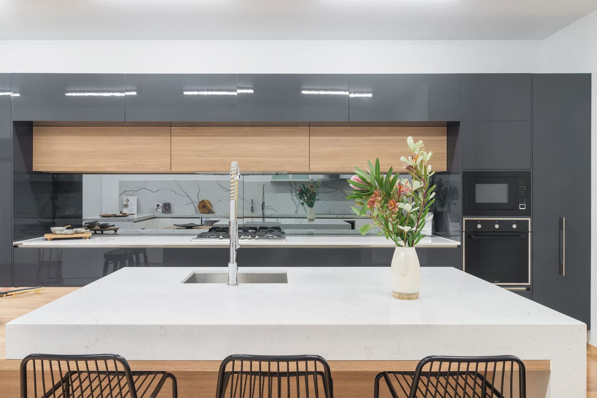 Modern Kitchen With White Island, Gray Cabinets, Wooden Accents, and a Vase of Flowers — Akyrah Kitchens in Gympie, QLD