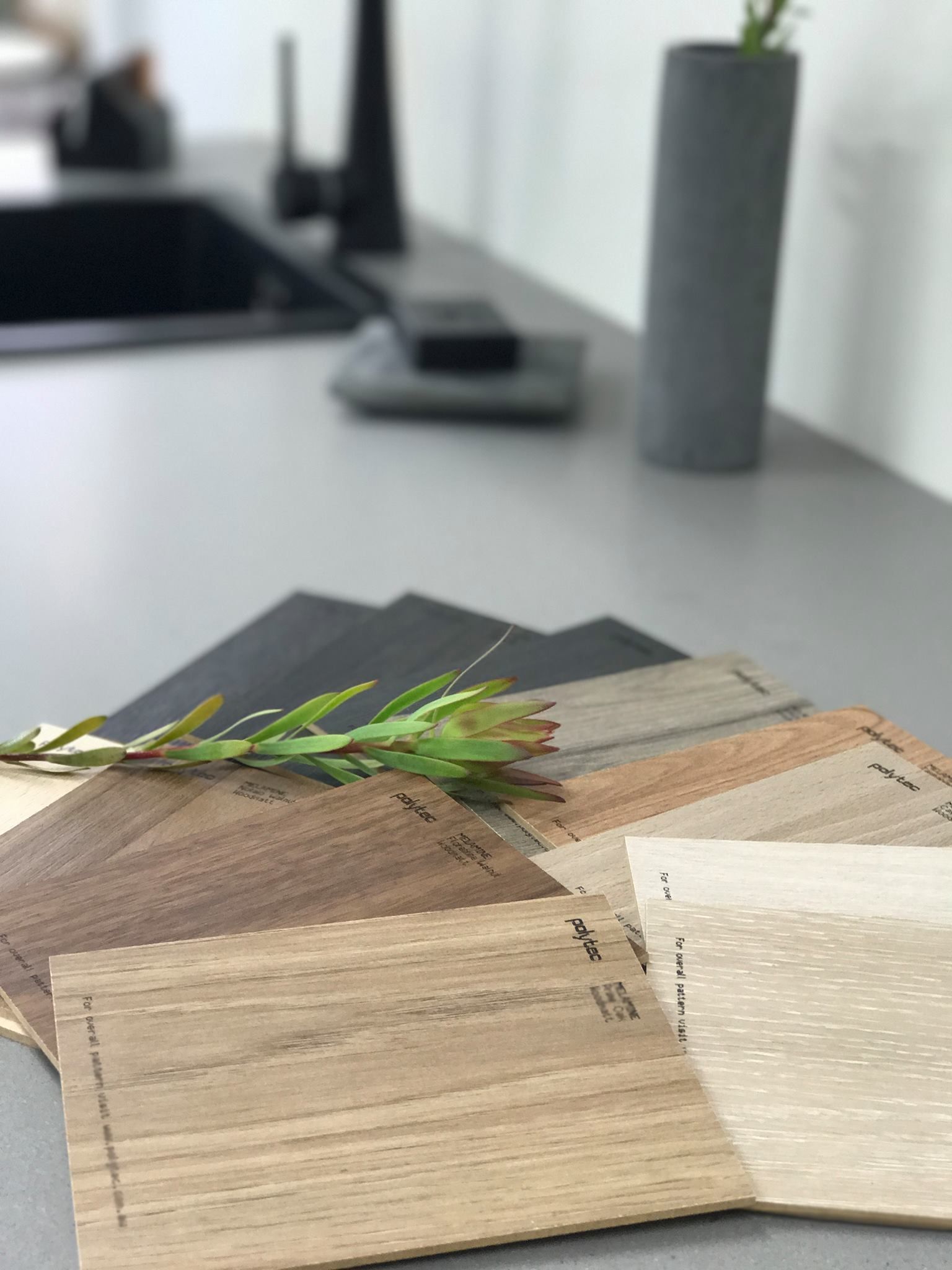 Wood and gray countertop samples with a kitchen sink in the blurred background. — Akyrah Kitchens in Gympie, QLD