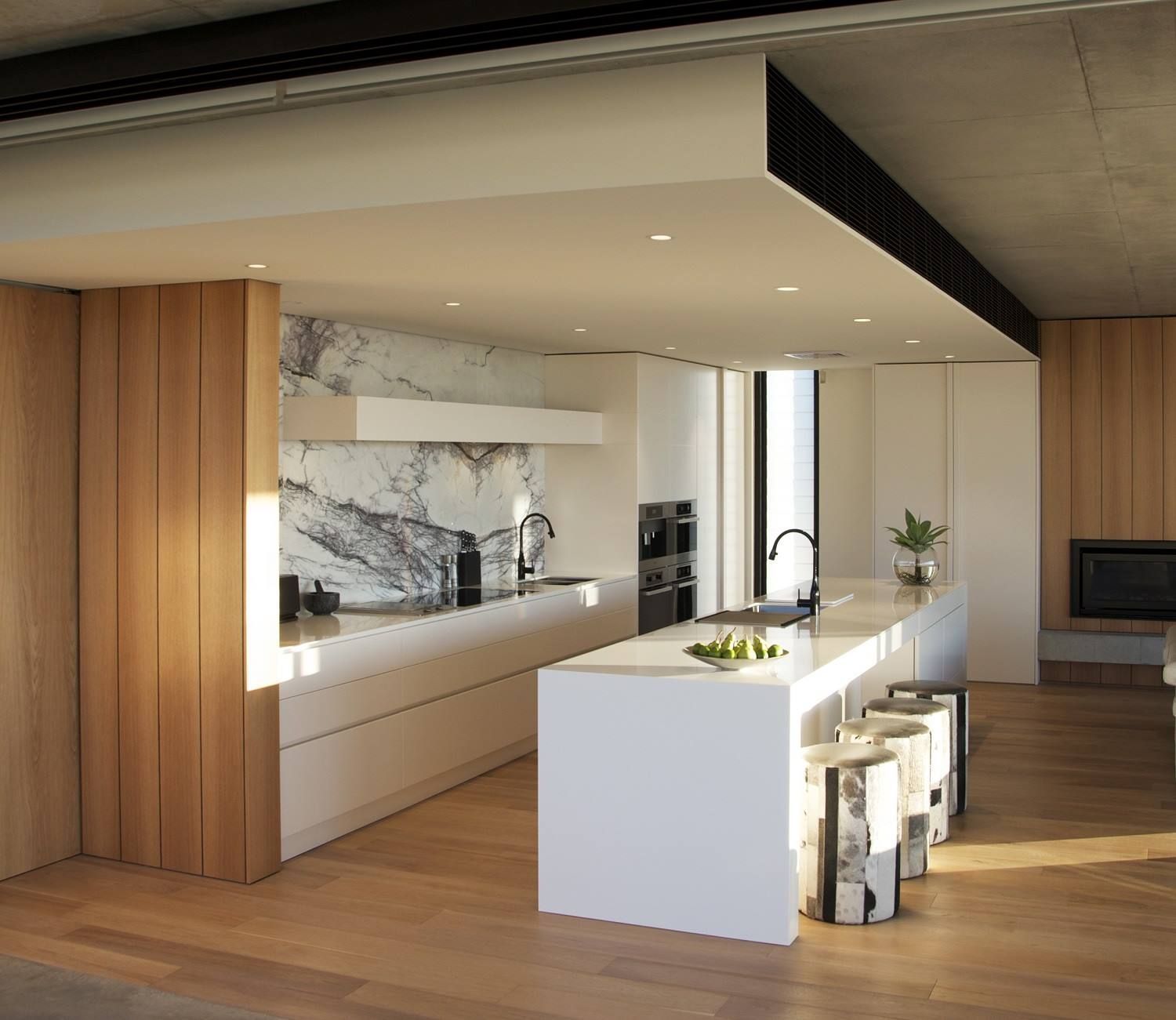 Modern kitchen with white cabinets, marble backsplash, wooden accents, and a large island with stools. — Akyrah Kitchens in Gympie, QLD
