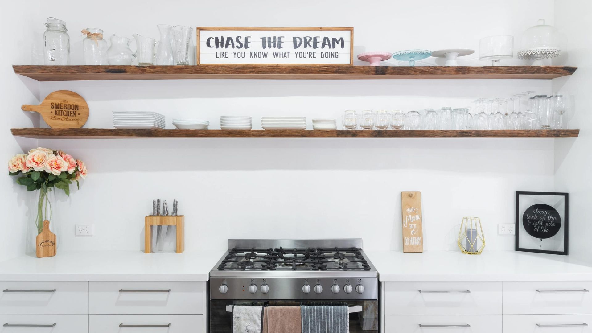 Kitchen With Open Wooden Shelves Displaying Dishes and Decor Above a Stainless Steel Stove — Akyrah Kitchens in Gympie, QLD