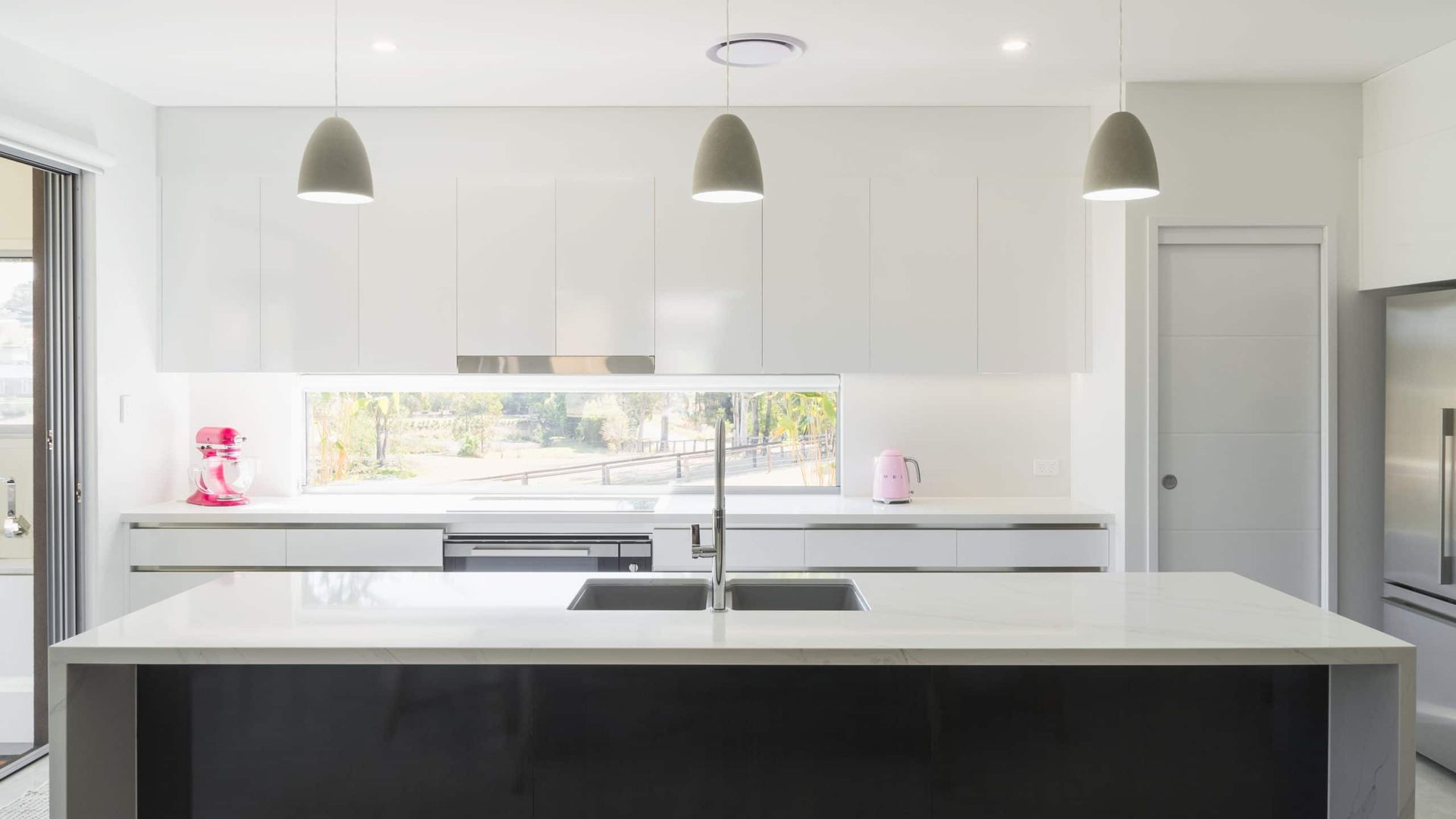 Modern White Kitchen With Island, Gray Cabinets, Three Pendant Lights, and Window — Akyrah Kitchens in Gympie, QLD
