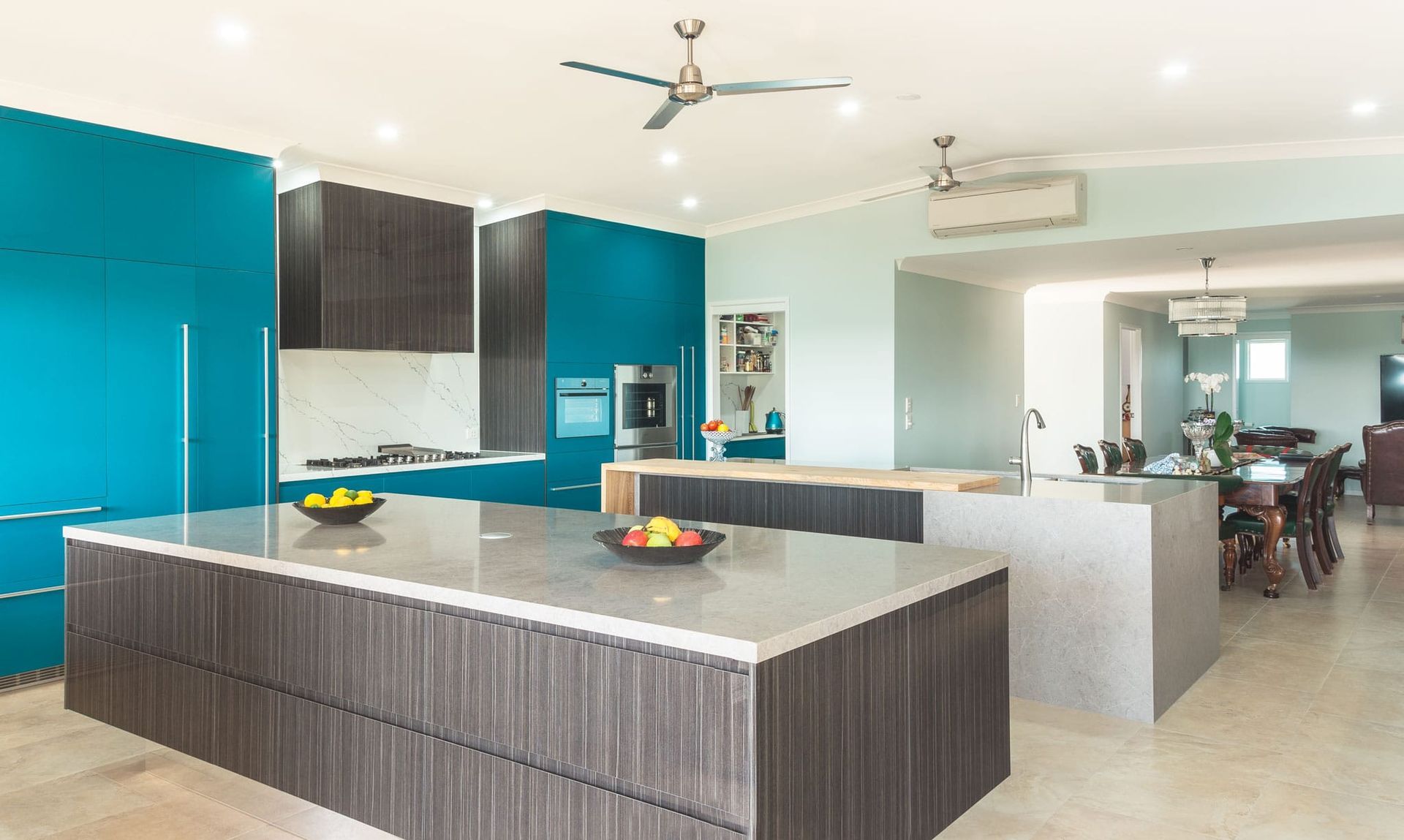 Modern Kitchen With Teal Cabinetry, Two Islands, and a Dining Area in the Background — Akyrah Kitchens in Gympie, QLD