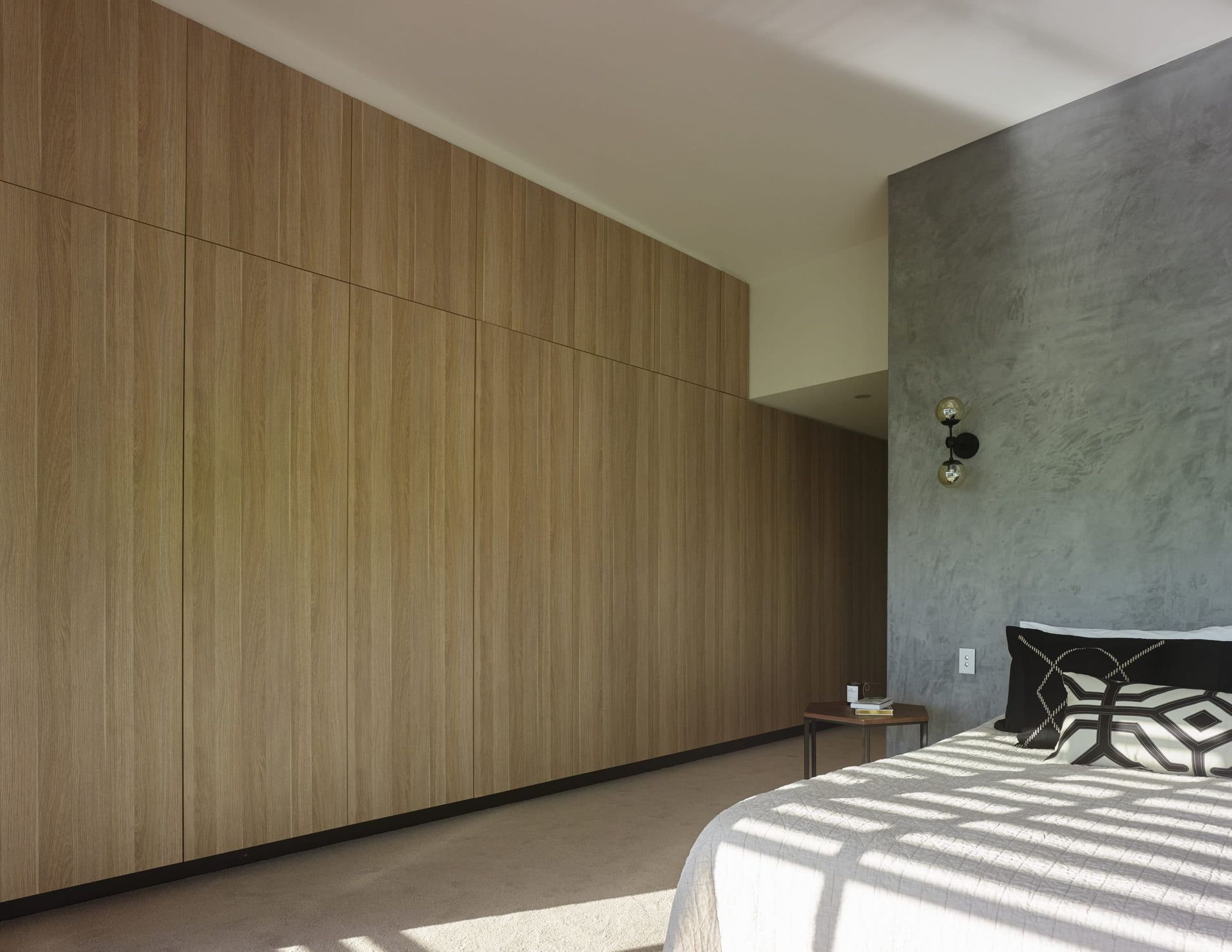 Bedroom With Light Wood Closet Doors, Gray Textured Wall, Bed With Patterned Pillow — Akyrah Kitchens in Gympie, QLD