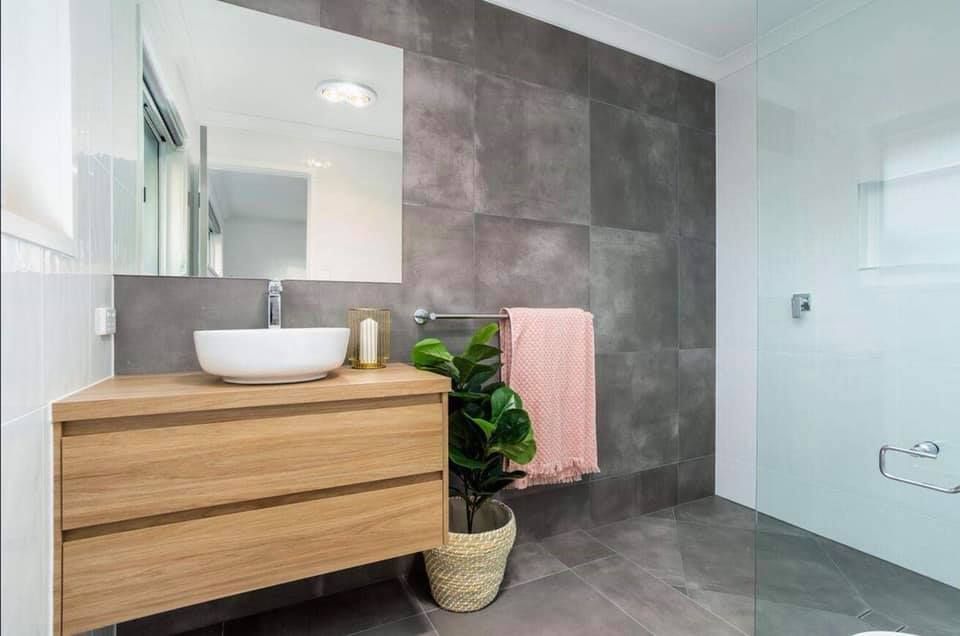 Modern Bathroom With Wood Vanity, White Sink, Gray Tile Wall, and Pink Towel — Akyrah Kitchens in Gympie, QLD