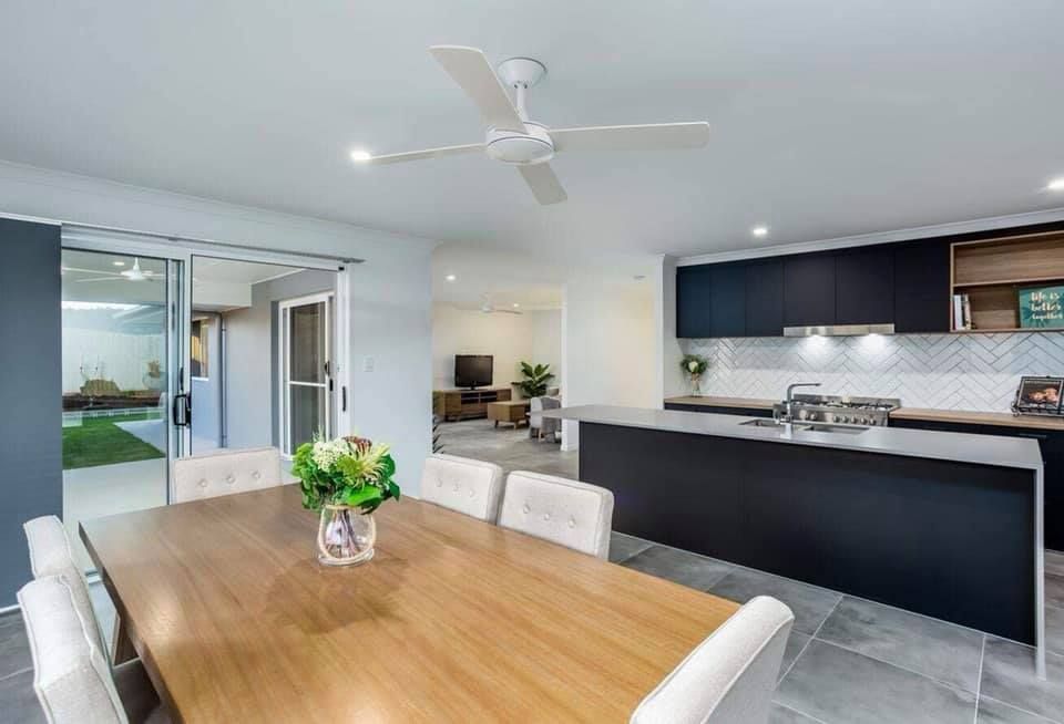 Dining Area With Table, Chairs, and Kitchen Featuring Dark Cabinets and a Light Countertop — Akyrah Kitchens in Gympie, QLD