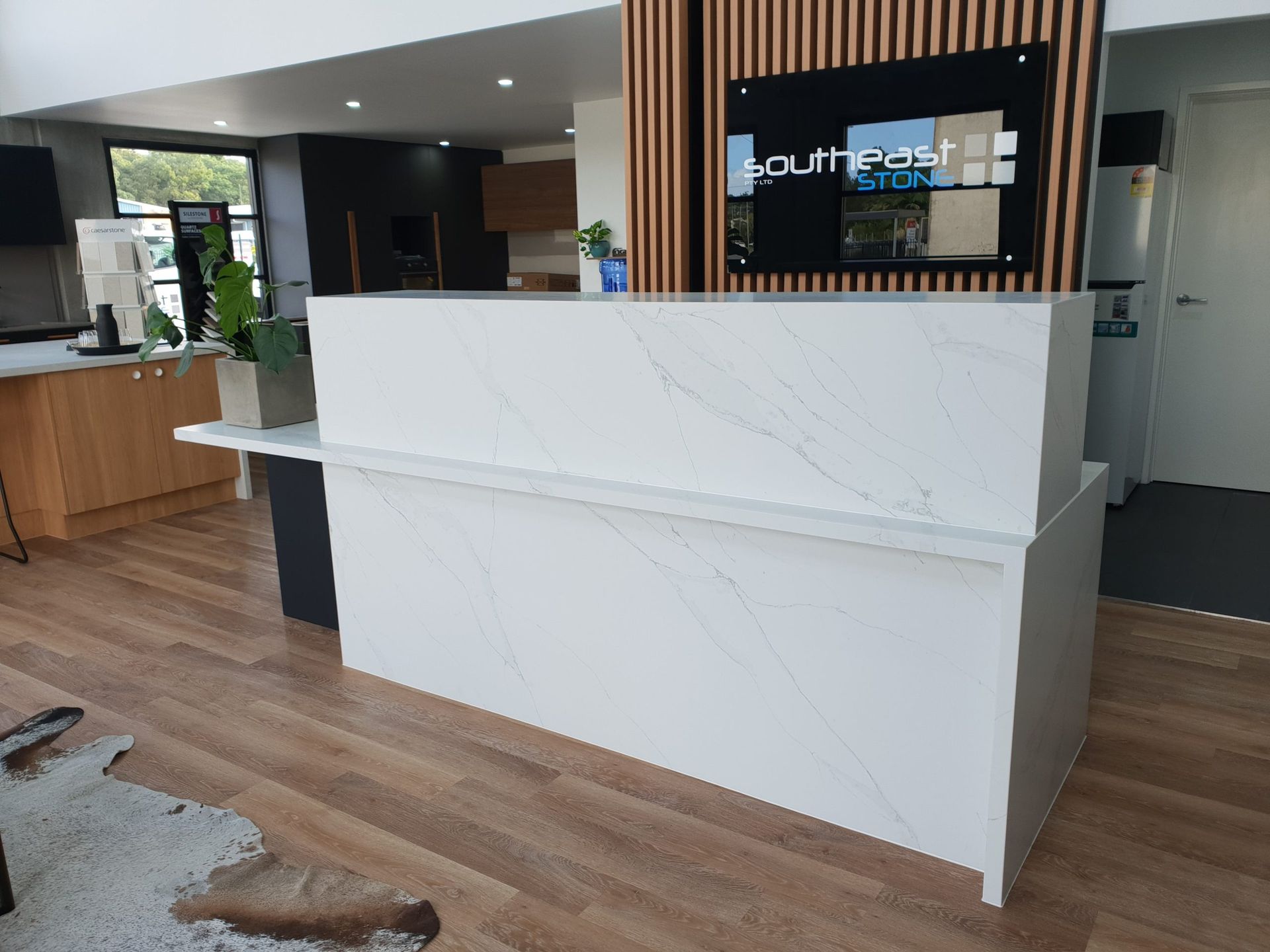 White Marble Reception Desk With a Company Sign in a Showroom — Akyrah Kitchens in Gympie, QLD