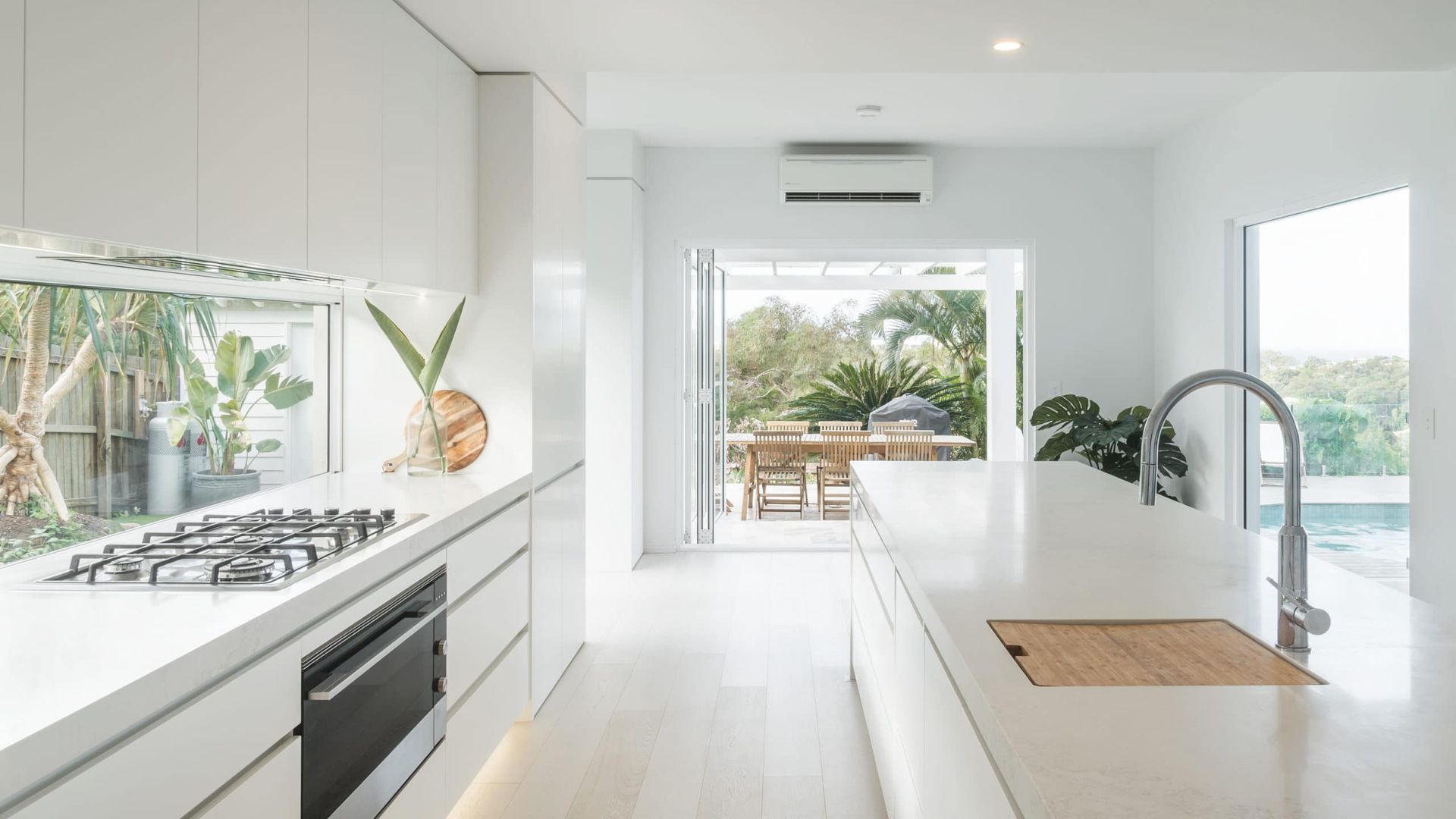 White Modern Kitchen With Island, Cooktop, and View to Patio — Akyrah Kitchens in Gympie, QLD