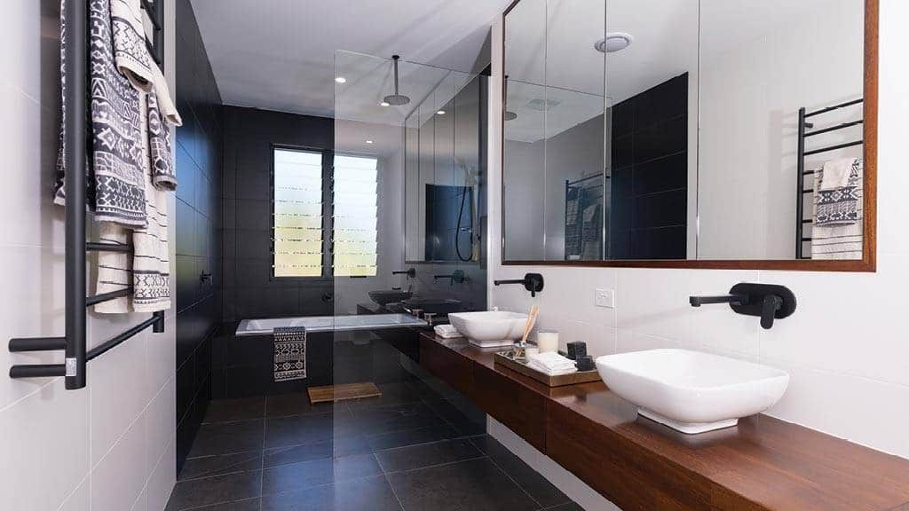 Modern Bathroom With Dark Accent Wall, Long Wood Vanity, Two Vessel Sinks, and Glass Shower — Akyrah Kitchens in Gympie, QLD