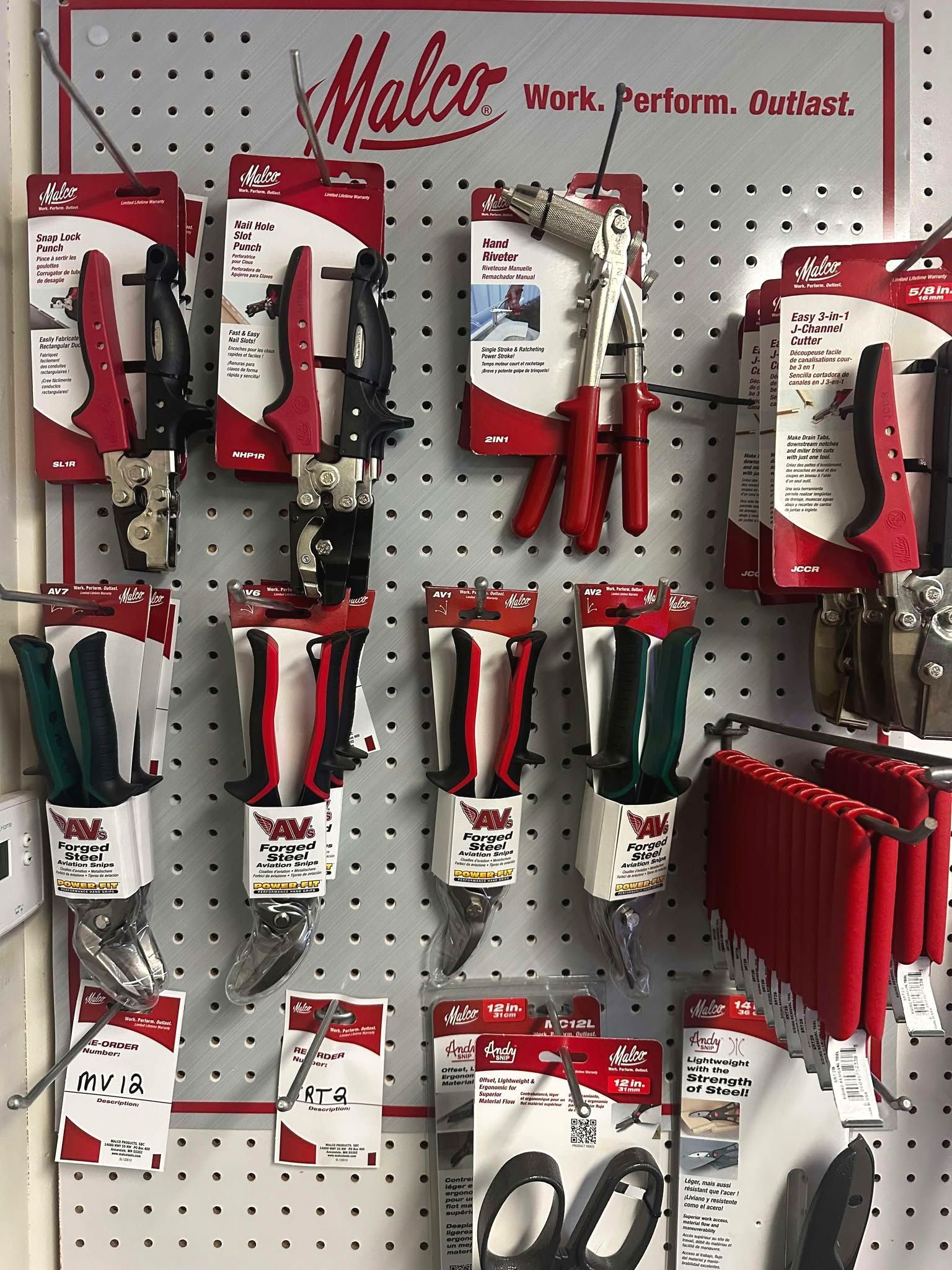 A variety of tools are displayed on a wall in a store.