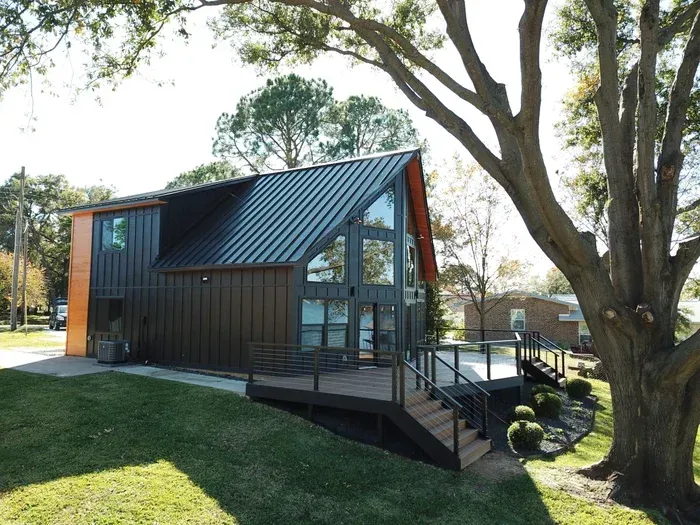 A house with a black roof and a large deck