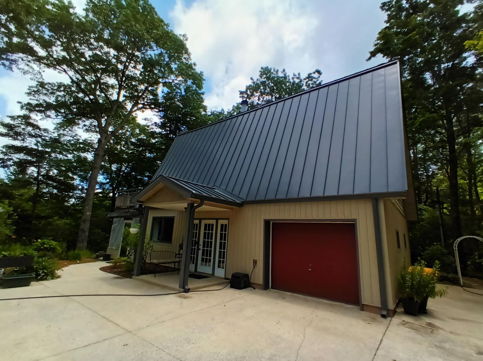 A small house with a black roof and a red garage door