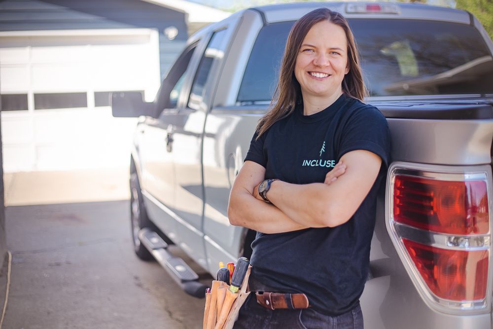 A woman is standing next to a truck with her arms crossed.