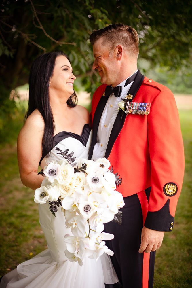 A bride and groom in military uniforms are posing for a picture.