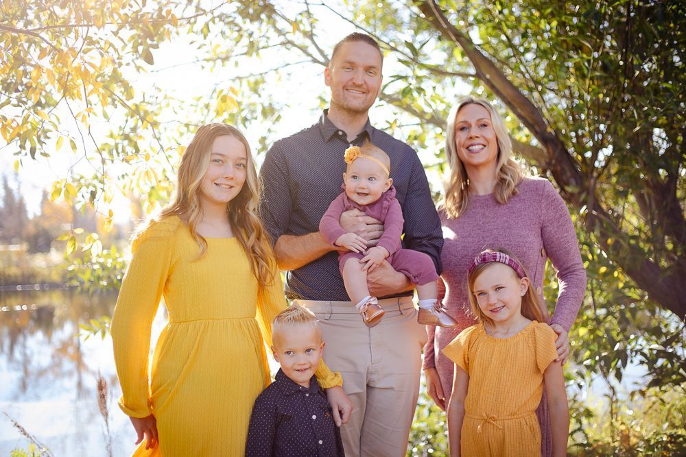 A family is posing for a picture in front of a lake.