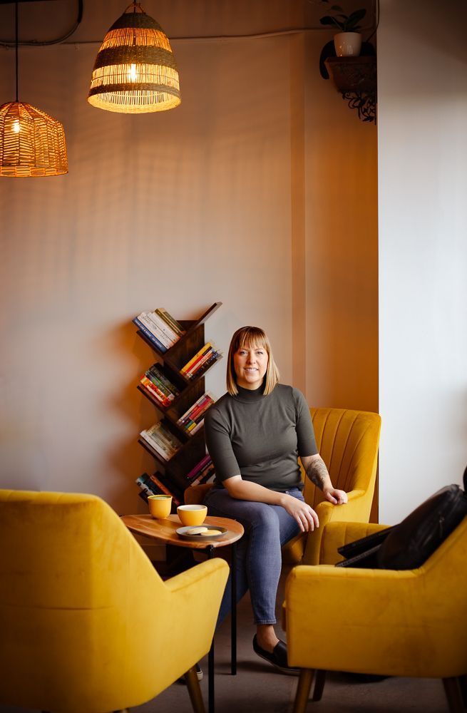 A woman is sitting in a yellow chair in a cafe.