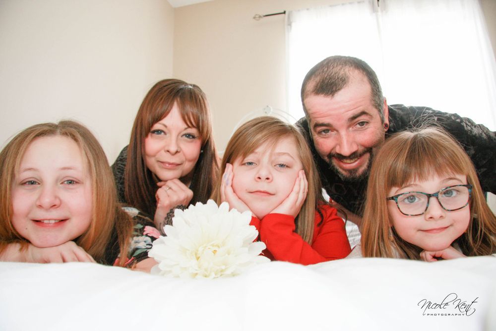 A family is posing for a picture while laying on a bed.
