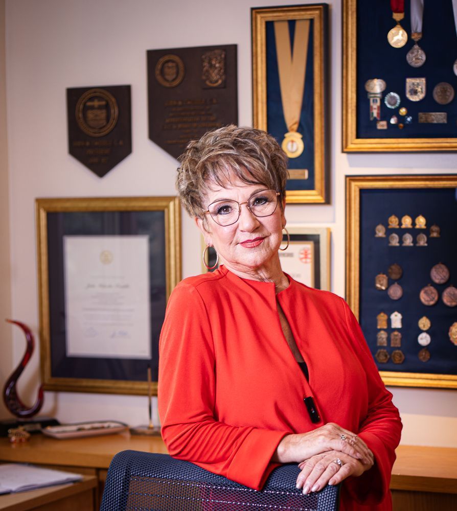 A woman in a red shirt is leaning on a chair