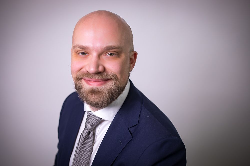 A bald man with a beard is wearing a suit and tie.