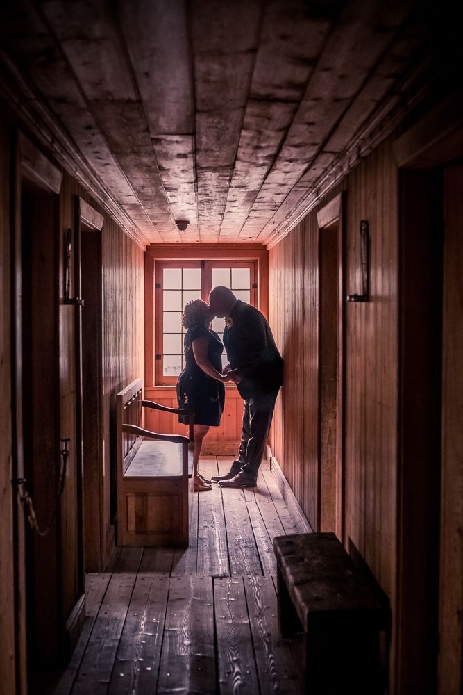 A man and a woman are kissing in a hallway.