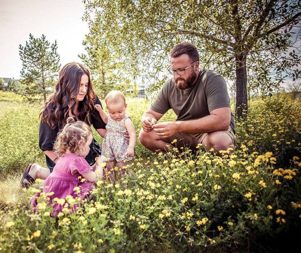 A family is sitting in a field of flowers.