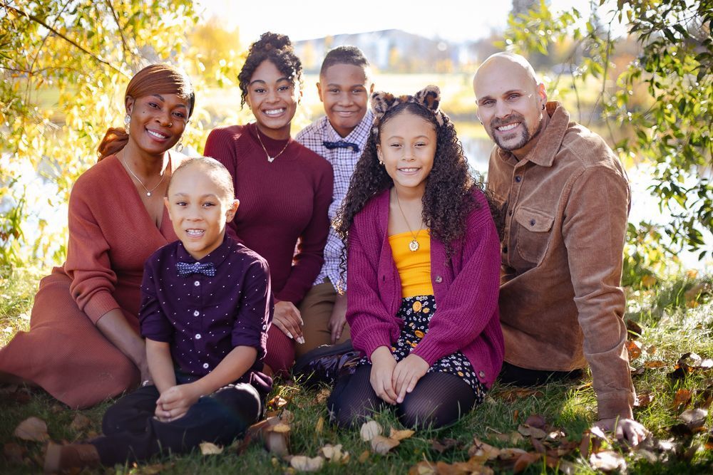 A family is posing for a picture while sitting in the grass.