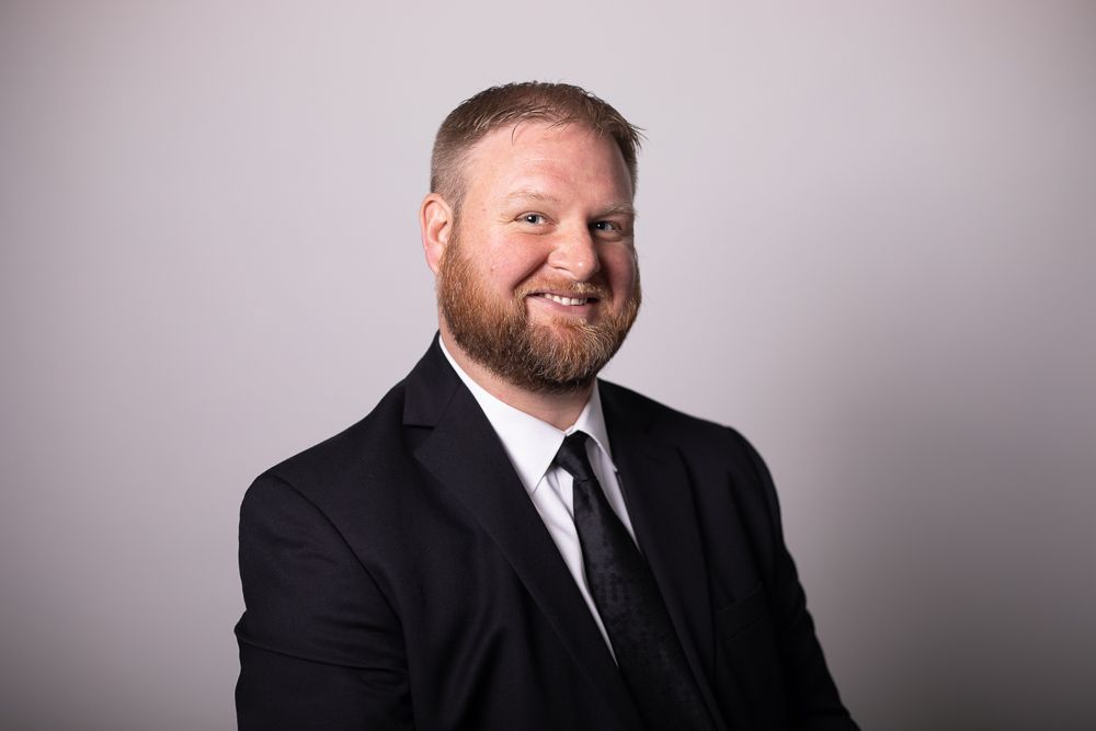 A man with a beard is wearing a suit and tie and smiling.