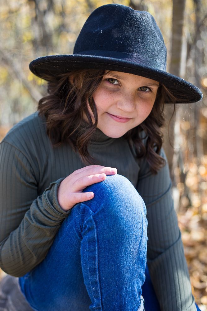 A young girl wearing a hat in the woods.