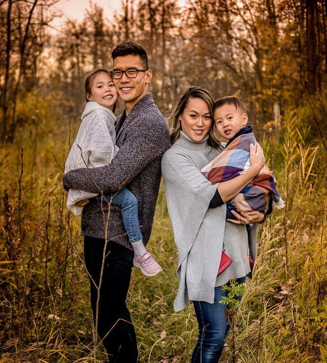 A family is posing for a picture in the woods.