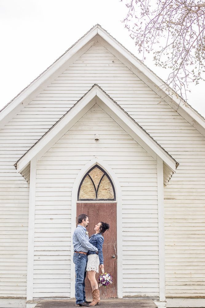 A man and woman are standing in front of a white church.