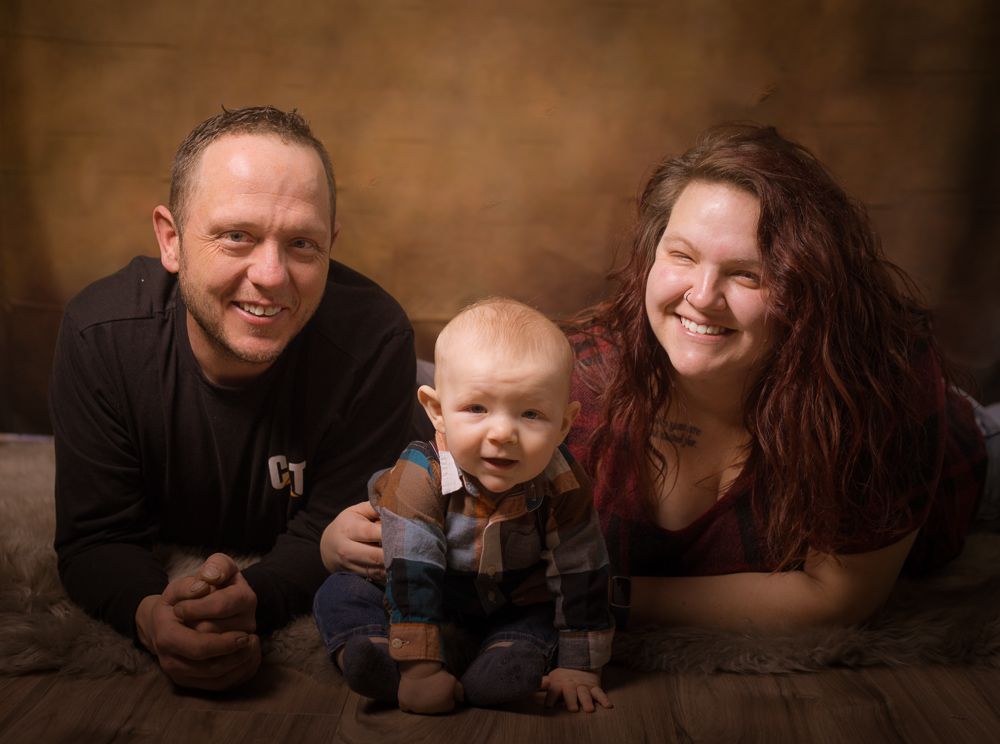 A man and a woman are laying on the floor with a baby.